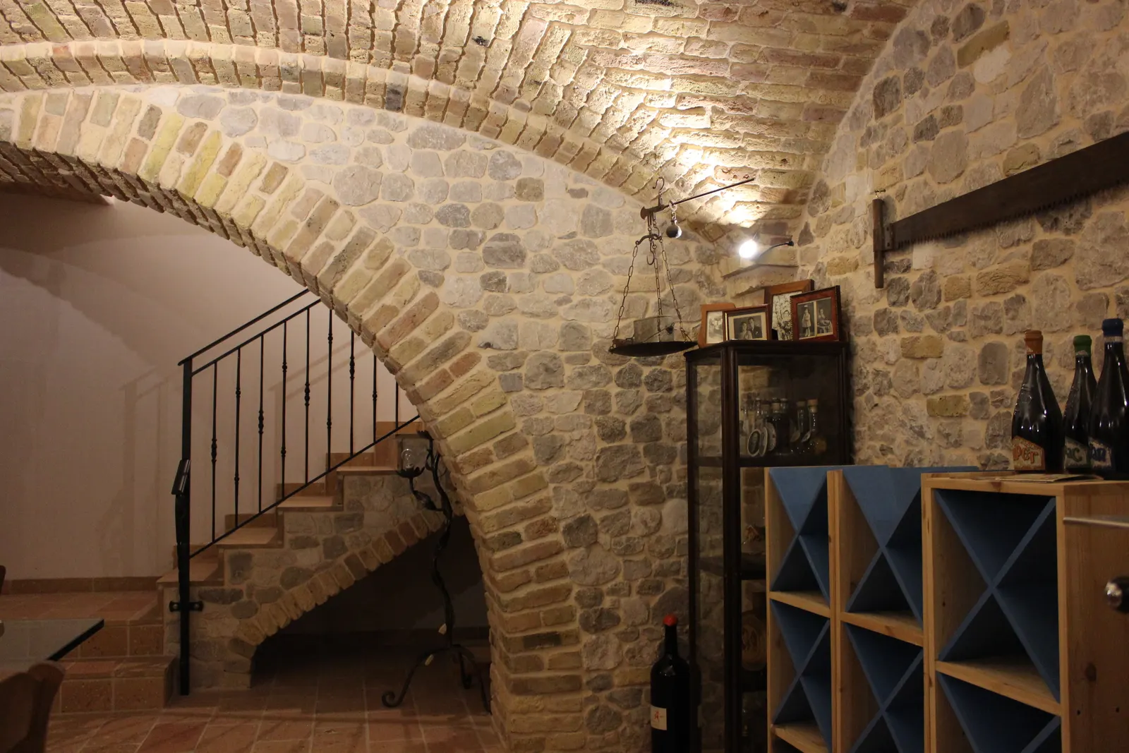 Wide open arch in reclaimed brick between the basement tavern and the staircase, with the space under the stairs left open — Flumignano, Italy