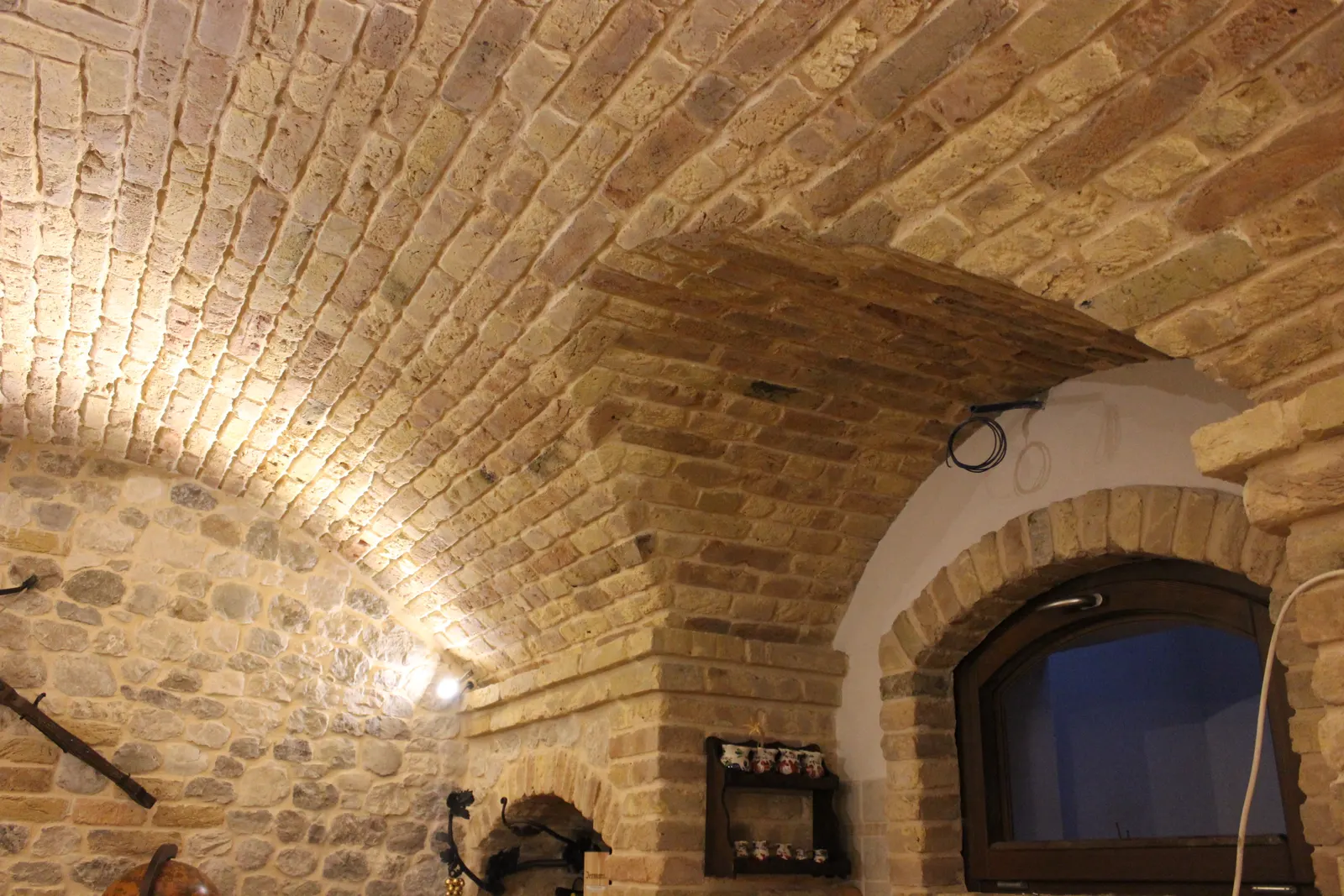 Lunette cut into the brick vault above the sink, in the cloister-vault end of the basement tavern — Flumignano, Italy