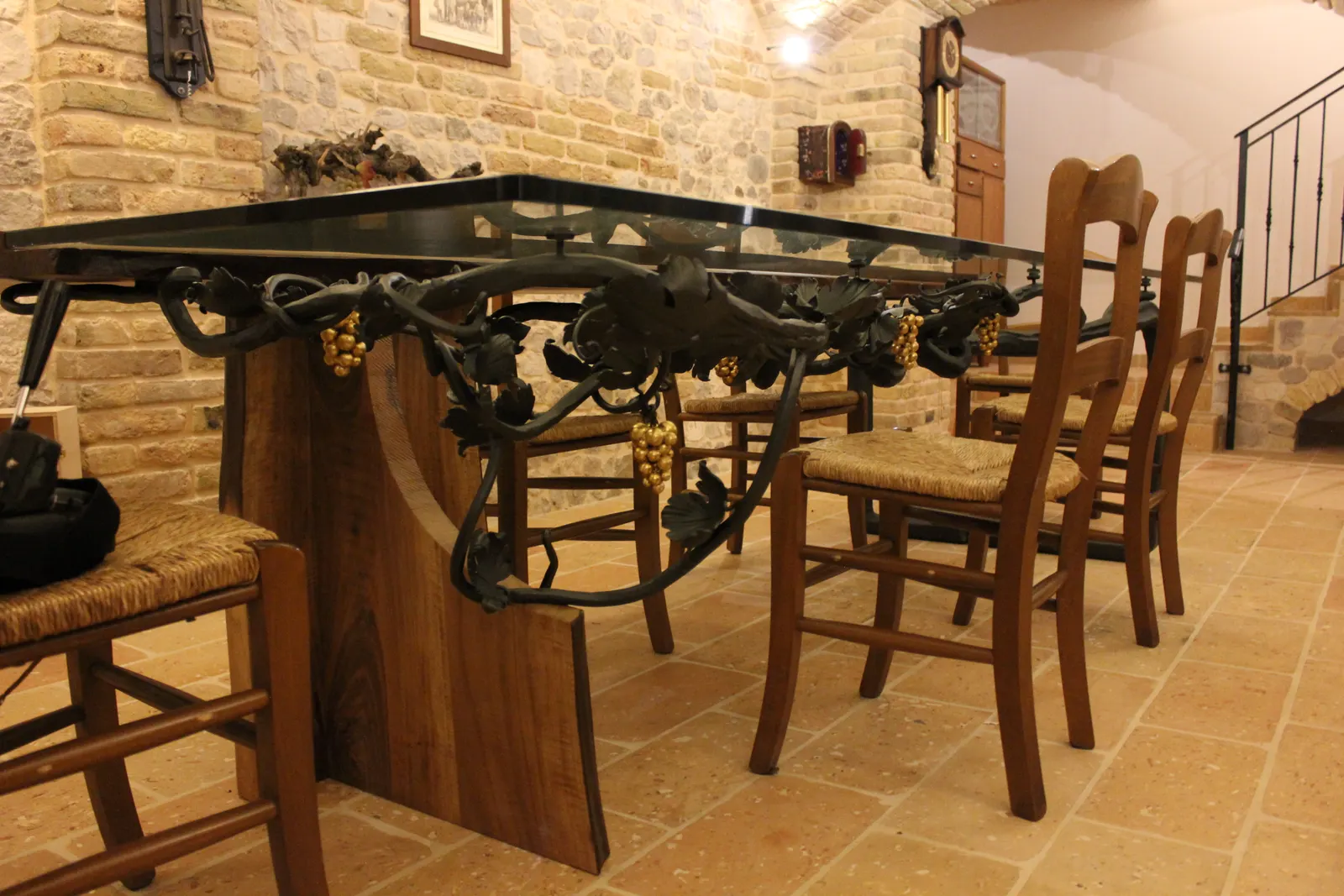 Hand-forged wrought iron table with a glass top, commissioned by the owner for the brick-vaulted tavern — Flumignano