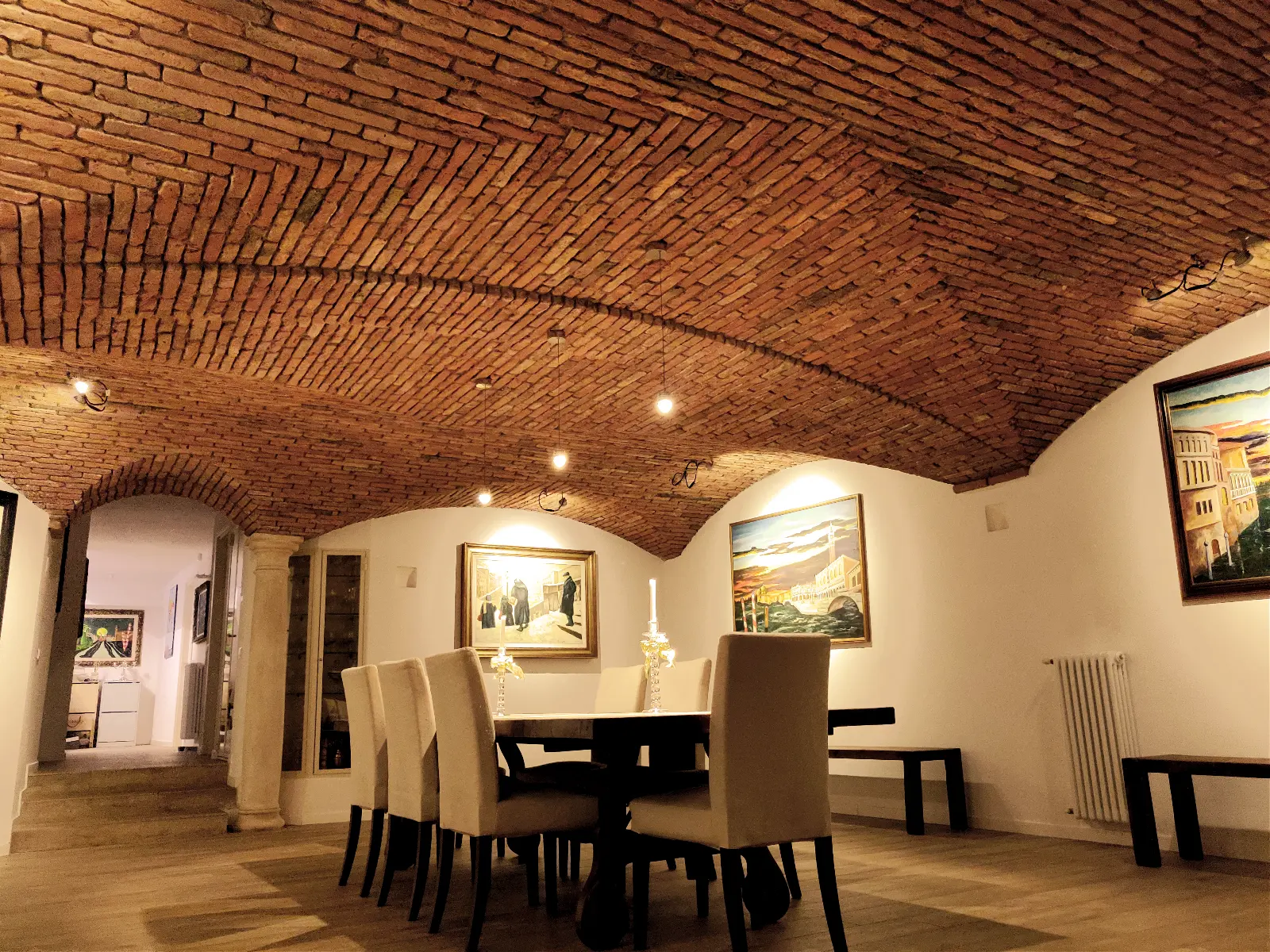 Luxury dining room where the warm brick cross vaults complement the owner's paintings.