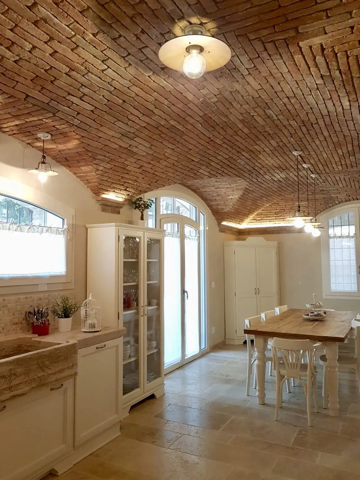 Tuscan style kitchen with exposed antique brick vaulted ceiling, cream cabinetry and stone farmhouse sink, by Pietrantiche
