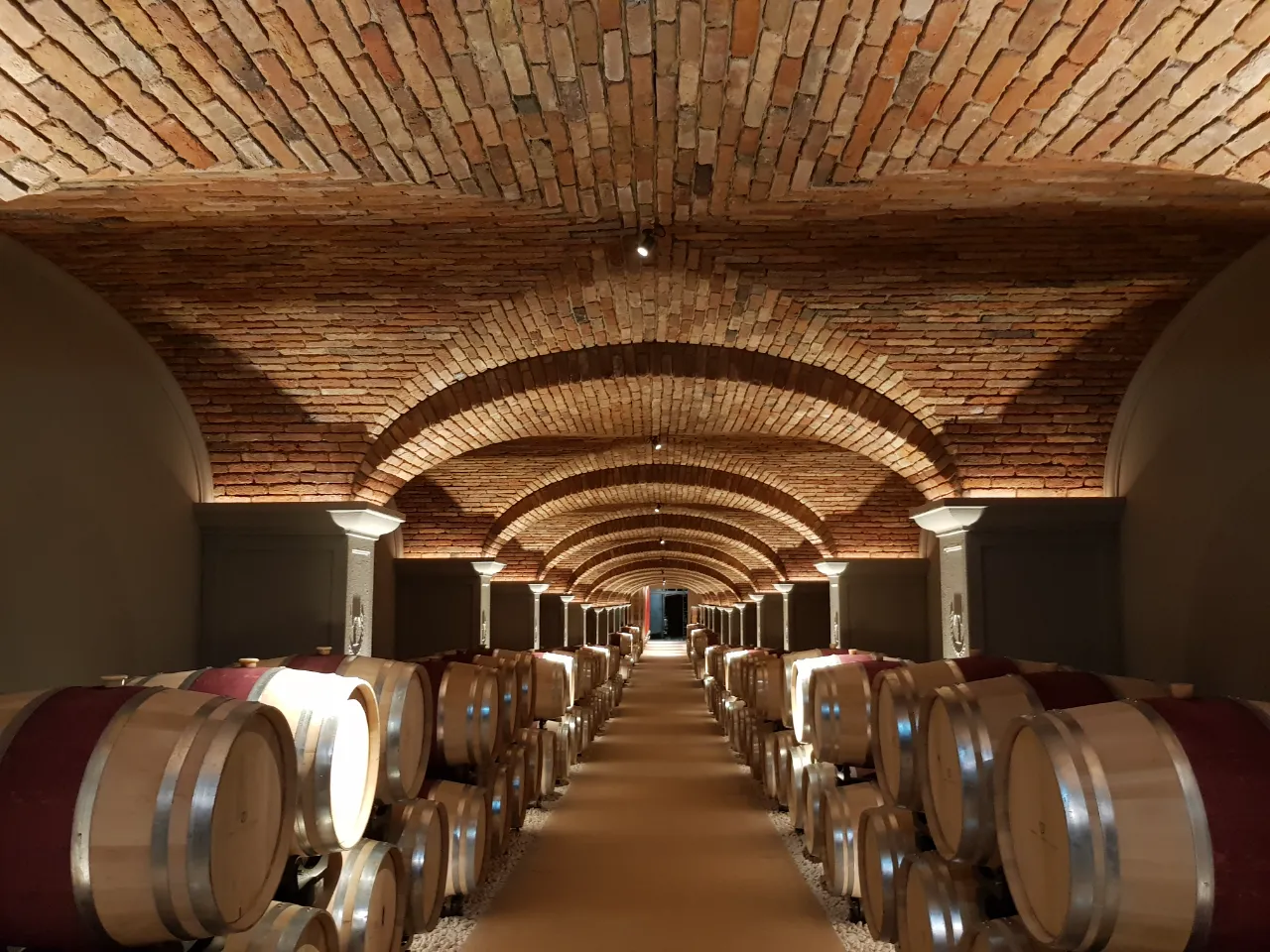 Bespoke luxury vaulted ceiling architecture: a long perspective of brick cross vaults crafted by Italian artisans, transforming a functional tunnel into a scenic and exclusive space.