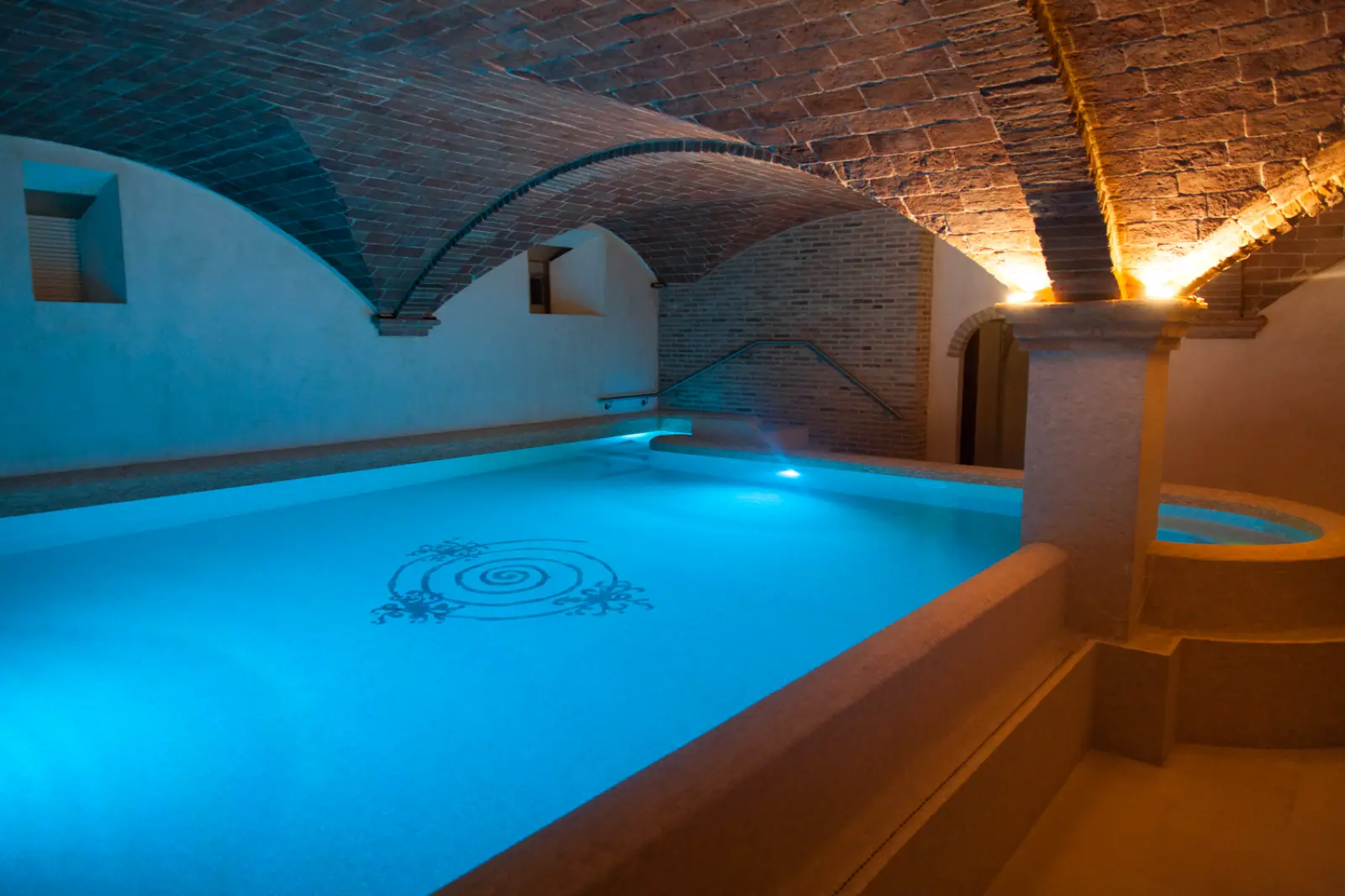 Bespoke brick cross vaulted ceiling designed for a luxury private indoor pool and spa. Flat-laid antique terracotta tiles create a continuous, elegant surface that softly reflects the lighting over the water.