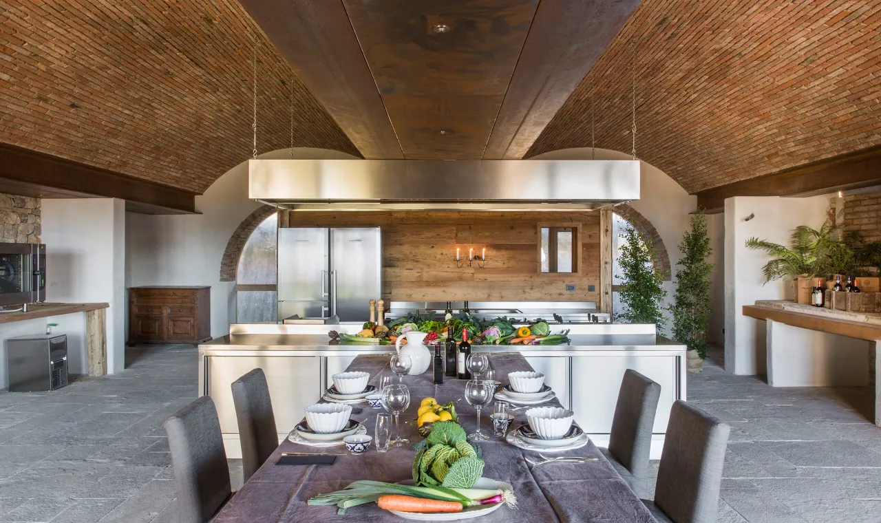 Bespoke antique brick barrel vaulted ceiling in a luxury Tuscan private villa, creating a stunning architectural contrast with a modern professional stainless steel kitchen.