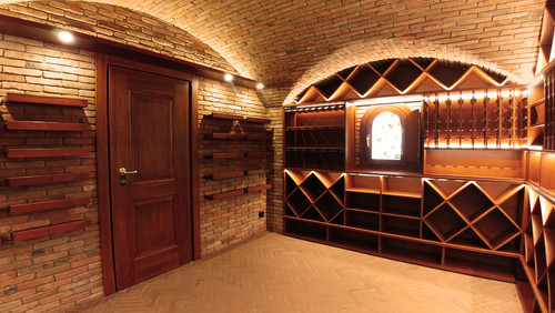 Cantina con volta in mattoni, scaffalatura e ripiani espositivi in legno su misura — cantina privata realizzata da Pietrantiche